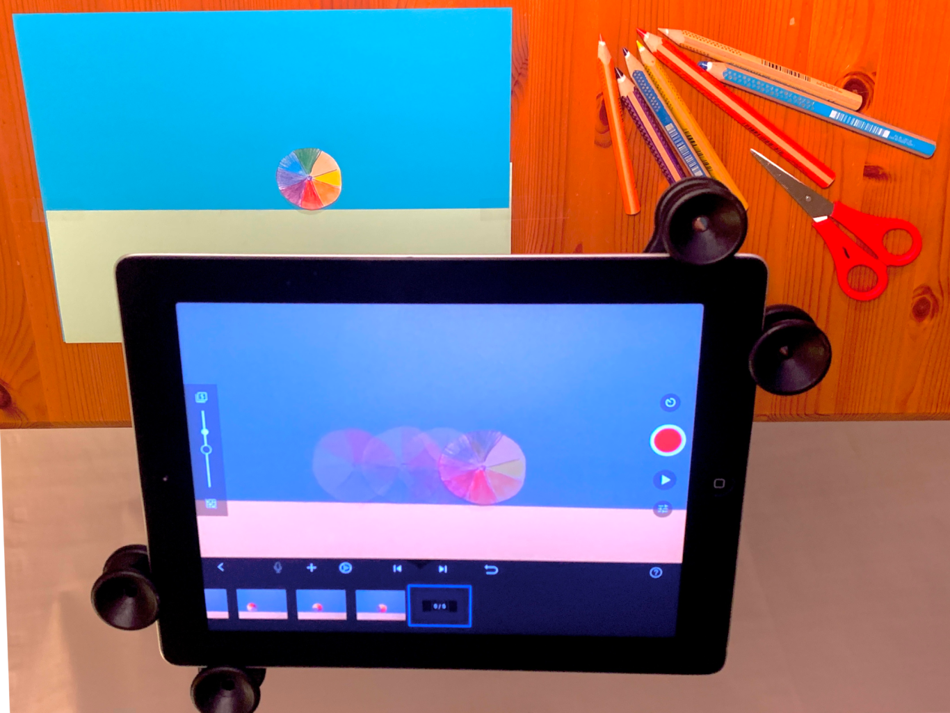 Ein Tablet zeigt eine kreative Stop-Motion-Sitzung mit Buntstiften, Schere und Papier